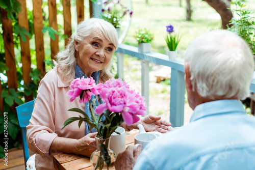 selective focus of happy senior woman looking at husband near pink flowers © LIGHTFIELD STUDIOS