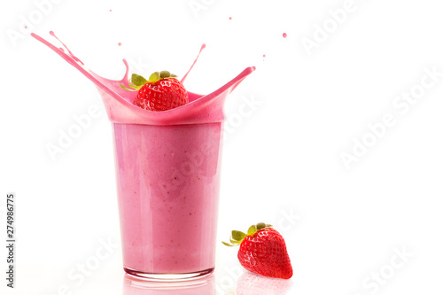 Delicious strawberries falling into a glass of strawberry milkshake on white background. Fresh strawberries falling into a glass to make a delicious and healthy strawberry milkshake.