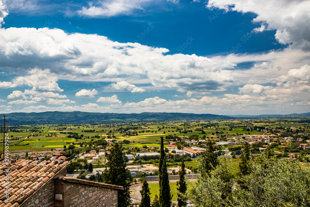 A panoramic view from the Spello viewpoint. The outskirts with the houses, the countryside, the nature, the cultivated fields, the mountains in the distance. Agriculture, lifestyle, wellness.