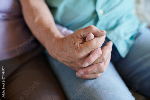 Senior man in blue jeans holding hand of his wife
