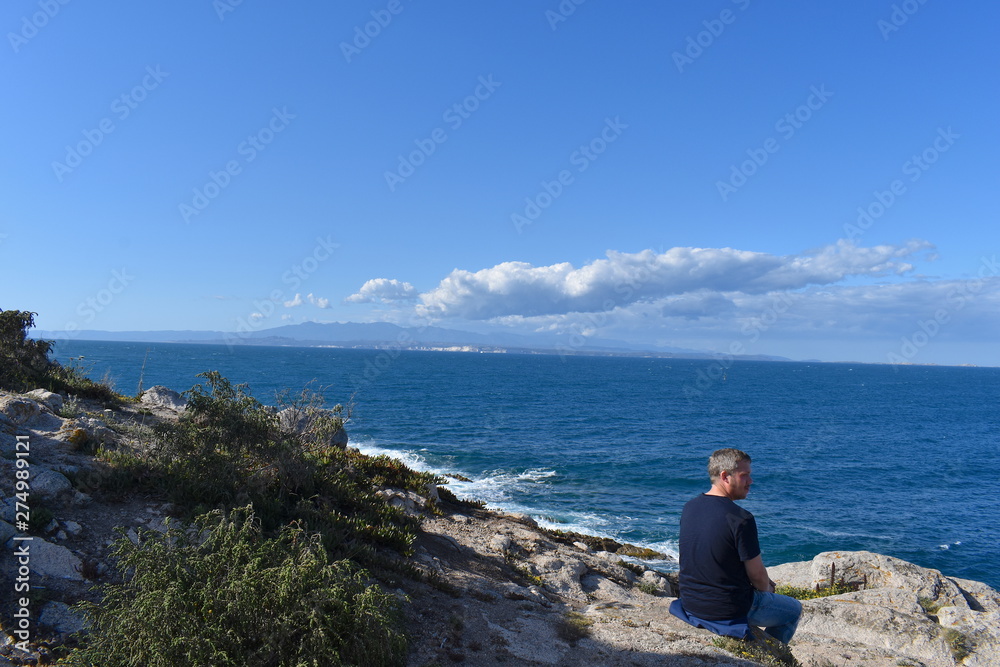 Man admiring the Sardinian coastline where colours of granite, coves and inlets make this part of the Italian island truly fascinating. Santa Teresa Gallura, Sardinia, Italy, May, 2019