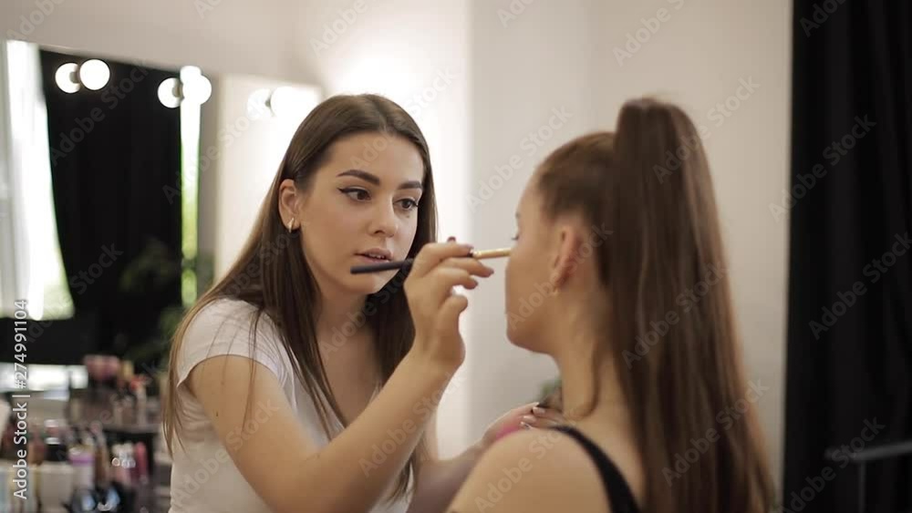 Makeup artist work in her beauty studio. Woman applying by professional make up master. Beautiful make up artist make a makeup for redhead model with freckles. She use a palette Makeup artist work in her beauty studio. Woman applying by professional make up master. Beautiful make up artist make a makeup for redhead model with freckles. She use a palette