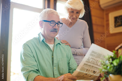 Serious matue man reading fresh news to his wife photo