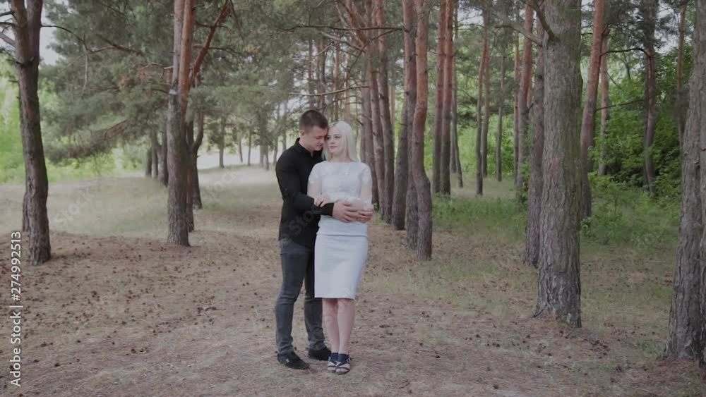 Beautiful and happy loving couple are tenderly embracing in the forest.