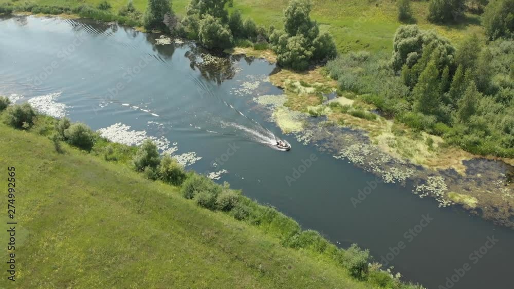 Aerial view. A small rubber fishing boat with a motor is moving quickly on a small river 4K Aerial view. A small rubber fishing boat with a motor is moving quickly on a small river 4K
