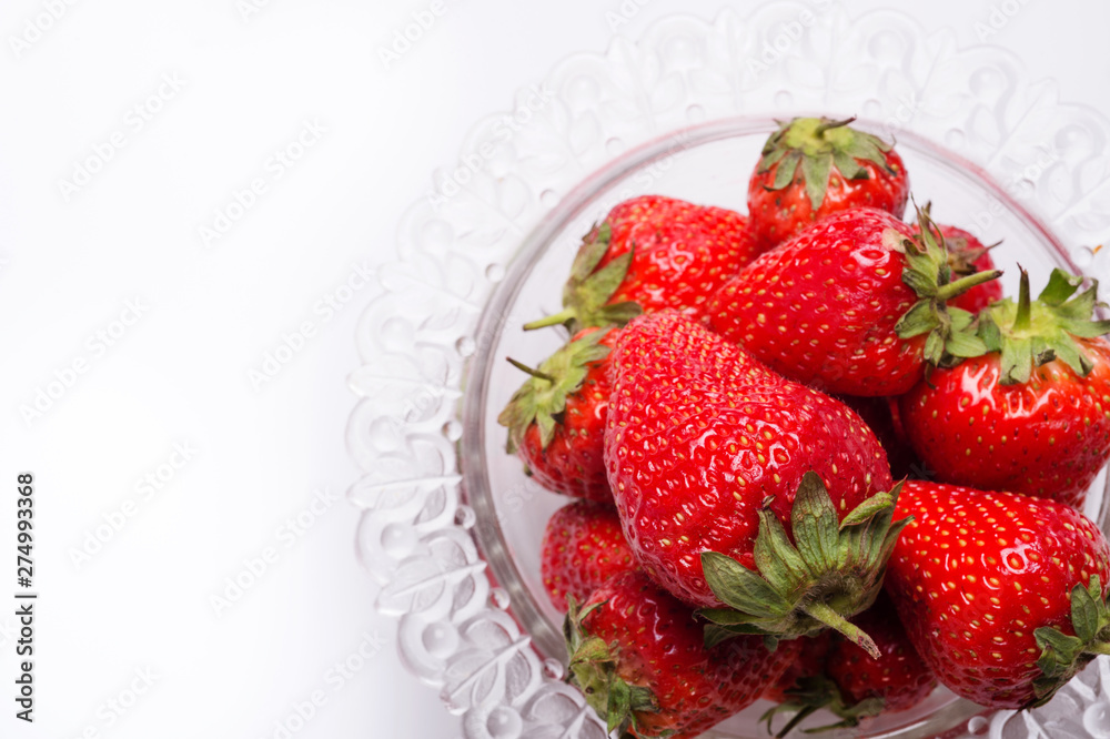 ripe strawberry in glass bowl around white. close up. flat lay