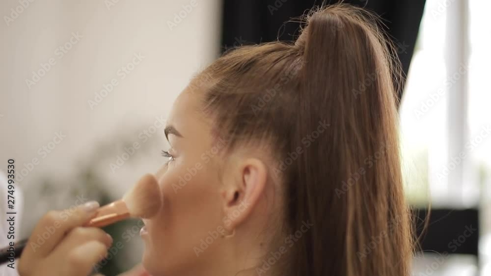 Makeup artist applies eye shadow, perfect evening makeup. Beauty redhead girl with perfect skin and freckles