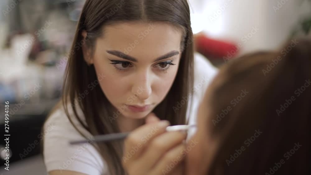 Beautiful makeup artist applies lipstick. Hand of make-up master, painting lips of young beauty redhead model. Make up in process Beautiful makeup artist applies lipstick. Hand of make-up master, painting lips of young beauty redhead model. Make up in process