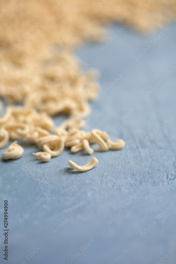 Homemade Small Macaroni Pasta Scattered on Blue Background