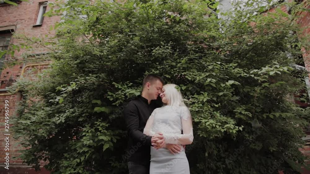 Happy loving couple basking in the branches of a green bush.