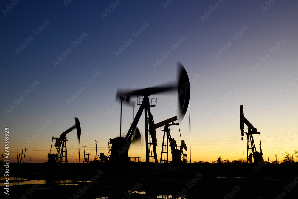 The pumping unit is working, silhouetted against the setting sun