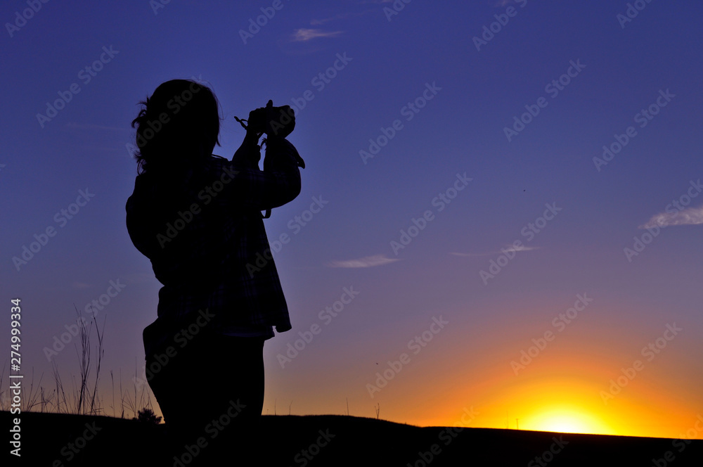 Woman taking pictures of sunset in São Francisco de Paula, Rio Grande do Sul, Brazil
