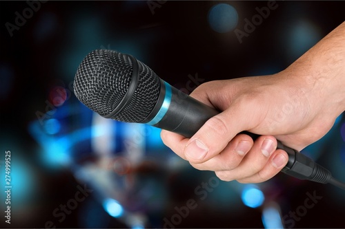 Hand holding microphone on blurred background