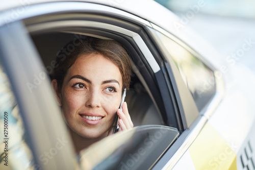 Head and shoulders portrait of beautiful woman speaking by phone in car looking out of window, copy space