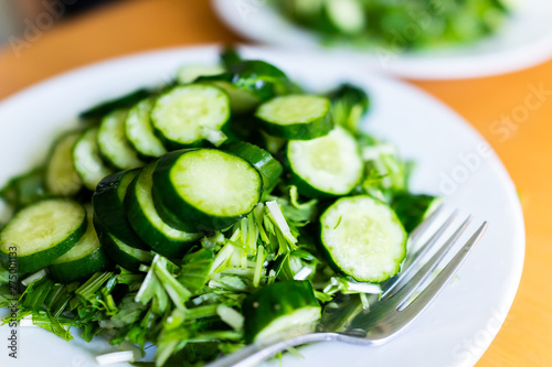 Home or restaurant with table and green salad dish closeup with Japanese cucumbers and mizuna greens