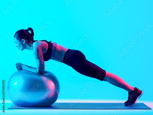 one mixed races woman exercsing fitness pilates exercices isolated on blue blackground