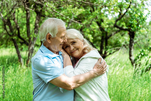 cheerful senior man hugging happy wife with grey hair