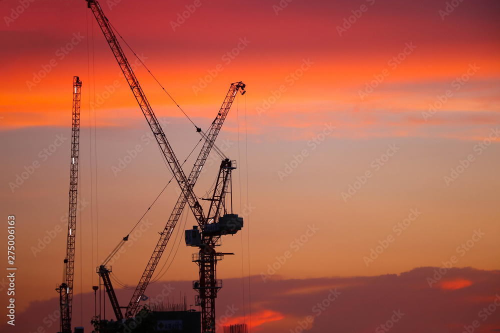 Silhouette construction crane with twilight orange color in the evening background