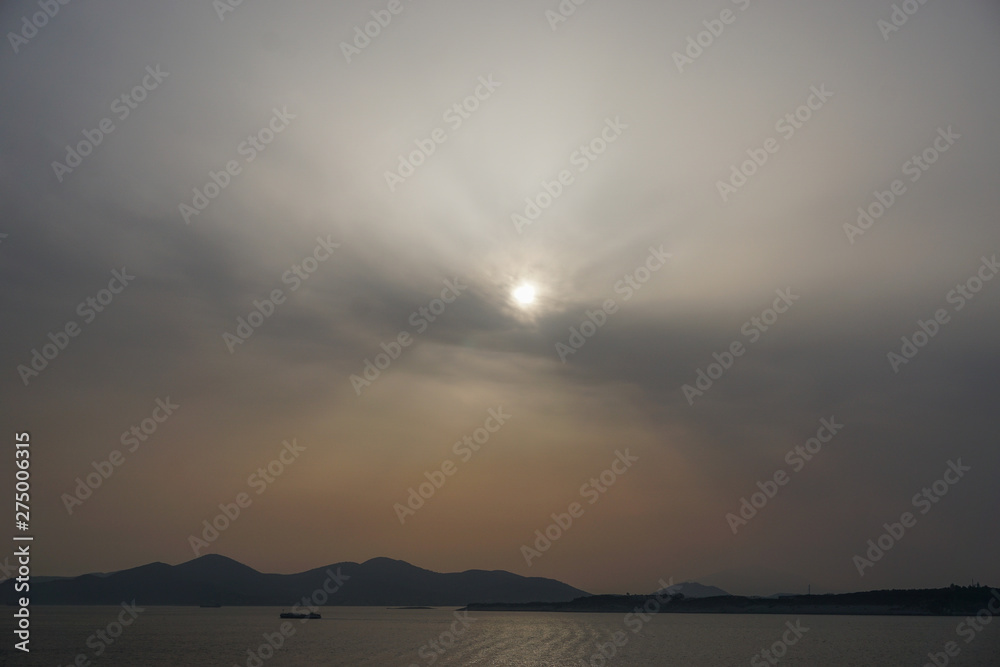 Piraeus, Greece: Sunset over islands in the Saronic Gulf (Gulf of Aegina) reveals a large amount of dust pollution in the atmosphere.
