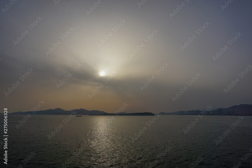 Piraeus, Greece: Sunset over islands in the Saronic Gulf (Gulf of Aegina) reveals a large amount of dust pollution in the atmosphere.