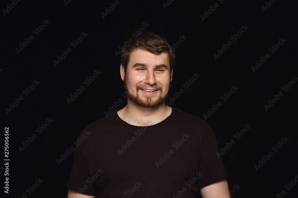 Close up portrait of young man isolated on black studio background. Photoshot of real emotions of male model. Crying throught laughting and smiling. Facial expression, human emotions concept. Close up portrait of young man isolated on black studio background. Photoshot of real emotions of male model. Crying throught laughting and smiling. Facial expression, human emotions concept.