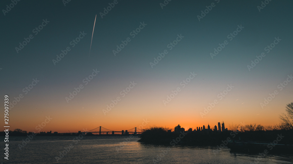 Sunset over philadelphia skyline with airplane streat