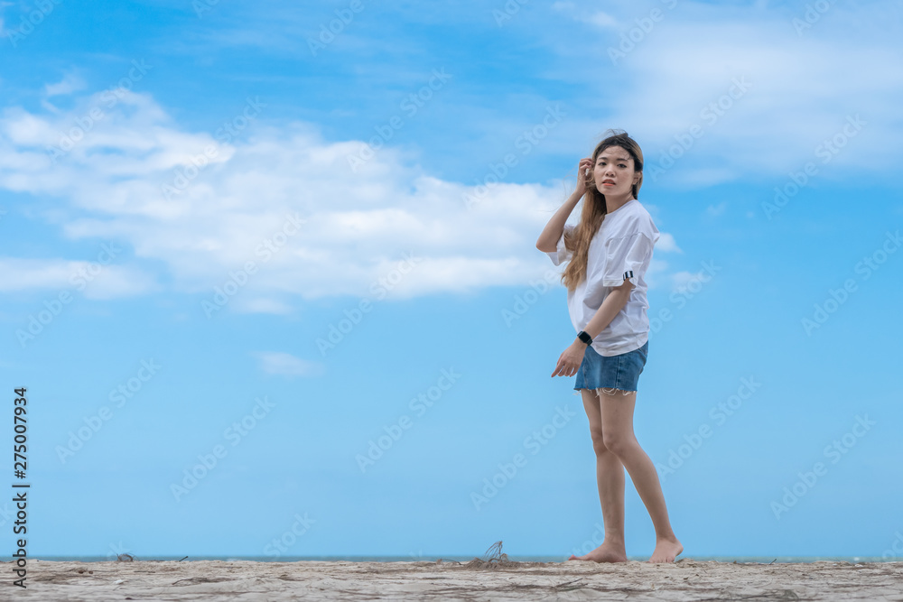 female standing on sandy beach with blue sky