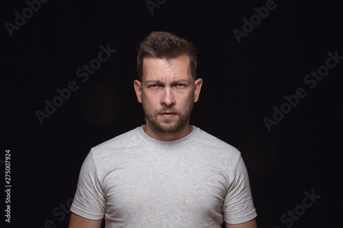 Close up portrait of young man isolated on black studio background. Photoshot of real emotions of male model. Crying, sad, angry and hopeless. Facial expression, human emotions concept. © master1305