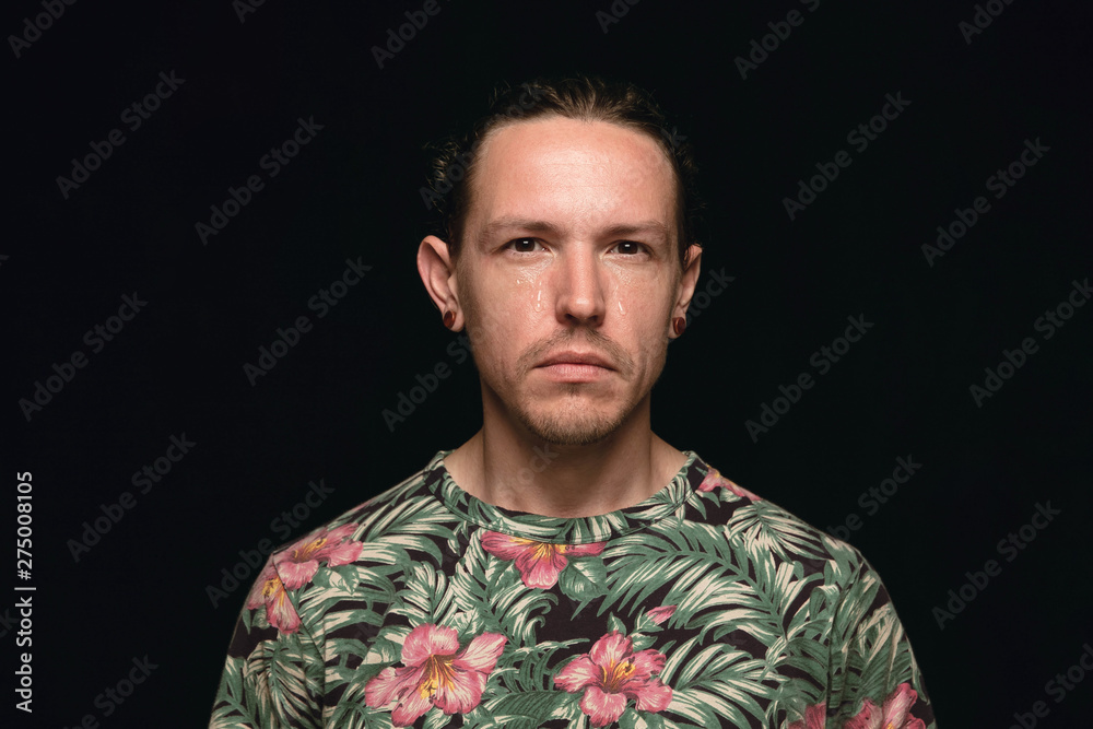 Close up portrait of young man isolated on black studio background. Photoshot of real emotions of male model. Crying, sad, dreary and hopeless. Facial expression, human emotions concept. Close up portrait of young man isolated on black studio background. Photoshot of real emotions of male model. Crying, sad, dreary and hopeless. Facial expression, human emotions concept.