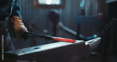 Close up of a red hot iron being hammered. Blacksmith hobbyist making metalworks out of iron in his forge.