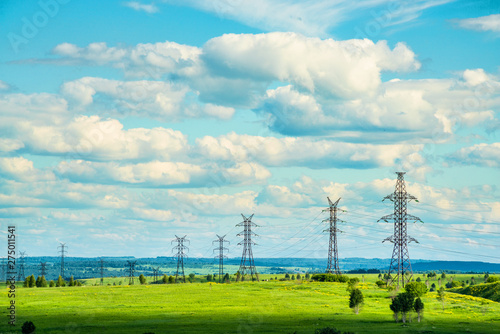 High voltage transmission towers on green grassland at sunny summer day  