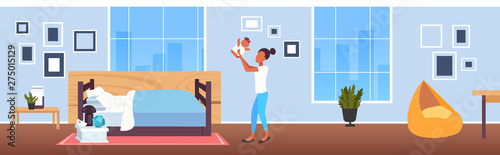 woman lifting up her little baby mother and newborn daughter having fun happy family motherhood concept modern bedroom interior cartoon characters full length horizontal