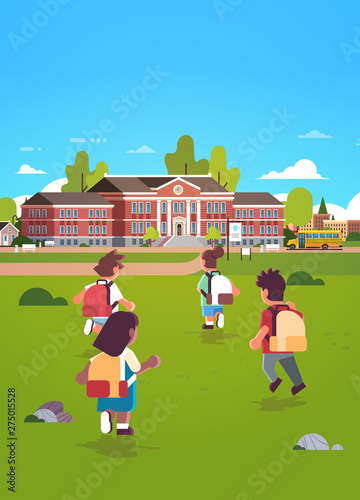 children group with backpacks running to school building education concept mix race rear view pupils in front yard green grass landscape background flat full length vertical