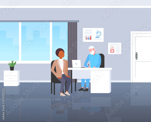 patient receiving a prescription african american man having consultation with senior doctor sitting at workplace medicine and healthcare concept modern hospital medical office full length flat