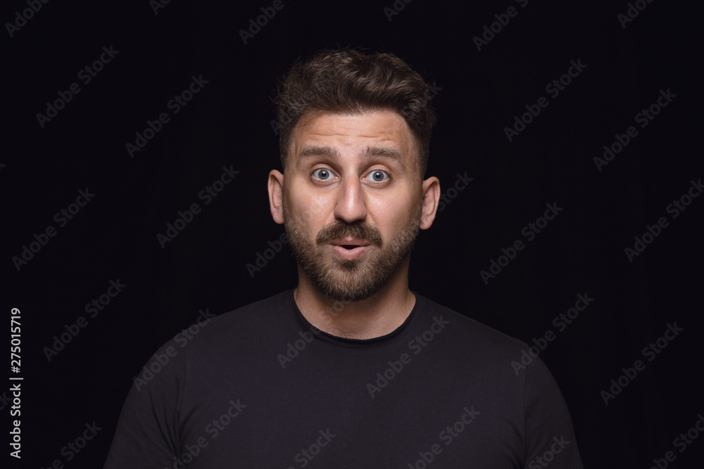 Close up portrait of young man isolated on black studio background. Photoshot of real emotions of male model. Wondering, exciting and astonished. Facial expression, human emotions concept.