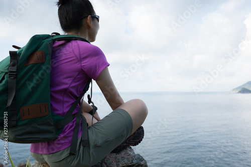 Woman hiker sit on seaside mountain peak cliff edge. © lzf