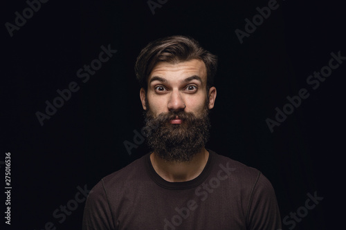 Close up portrait of young man isolated on black studio background. Photoshot of real emotions of male model. Wondering, exciting and astonished. Facial expression, human emotions concept.