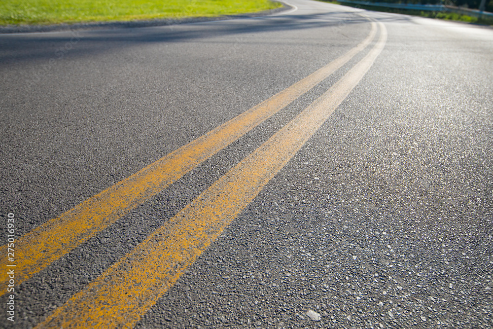 Asphalt Road With Double Yellow Lines And Green Grass To The Side. Selective Focus Road Travel And Transportation Concept.