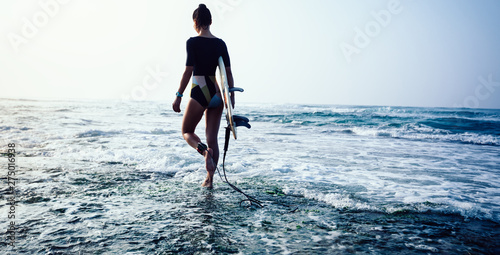 Photography Woman surfer with surfboard going to surf.