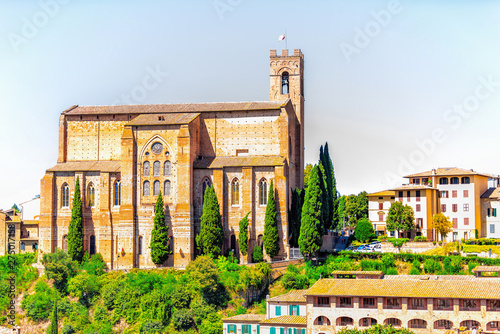 Siena, Italy city in Tuscany with view of San Domenico Church on sunny summer day with cypress trees
