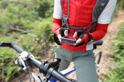Riding on summer hill, holding mobile phone, using online application for searching GPS coordinates while riding bike in forest on sunny day