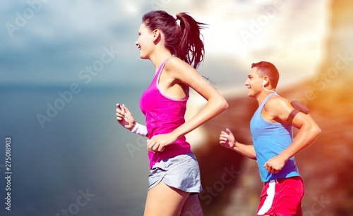 Fitness, sport, friendship and lifestyle concept - smiling couple running together
