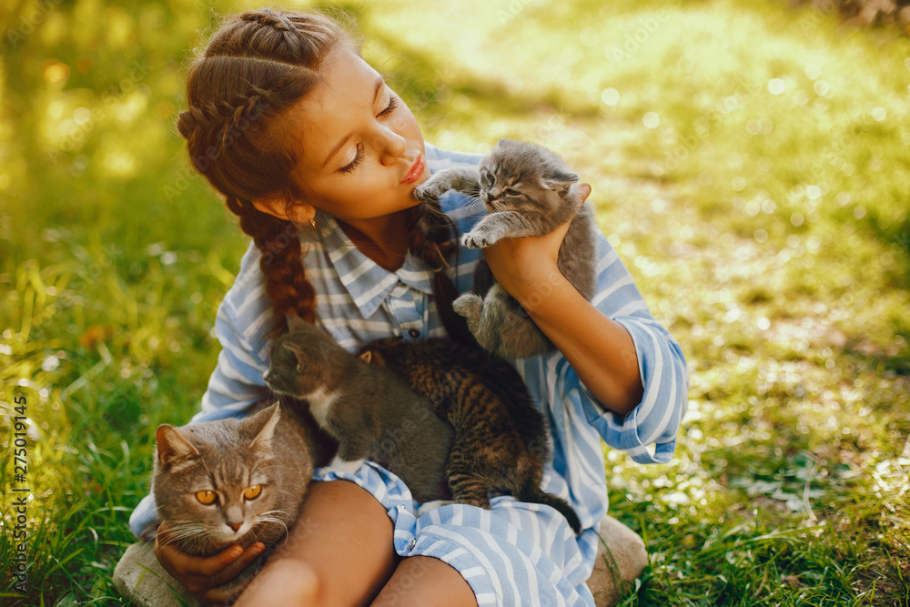 beautiful and cute girl in blue dresses with beautiful hairstyles and make-up sitting in a sunny green garden and playing with a cats beautiful and cute girl in blue dresses with beautiful hairstyles and make-up sitting in a sunny green garden and playing with a cats
