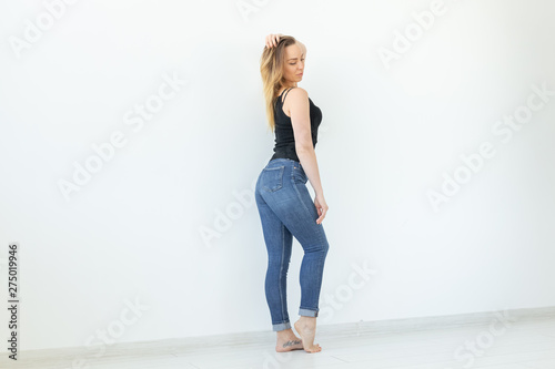 Style, people concept - young woman in jeans and black shirt standing over the white background with copy space