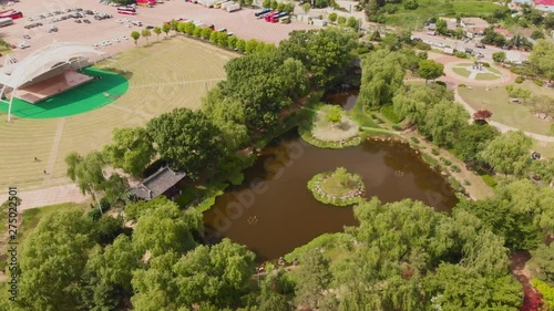 Aerial approach and tilt down towards asian pond in a park and outdoor performance stadium photo