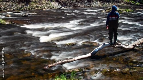 Timelapse man in waders walking around fast moving river. photo