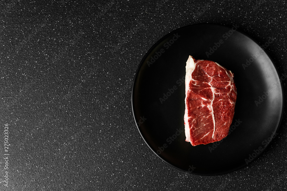 Raw prime beef top blade meat food steak against black stone background
