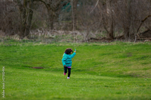 little girl running in park flying kite
