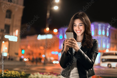 Young girl texting on phone  walking in city at night