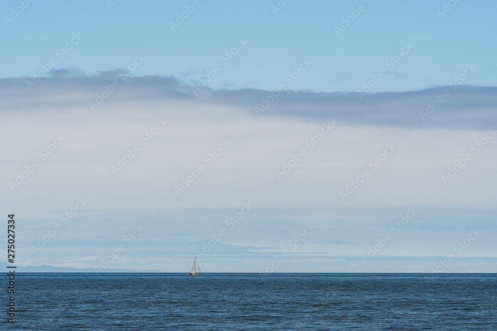 White sailboat cruising an a clam Salish Sea, San Juan Islands, blue sky with white clouds in the background